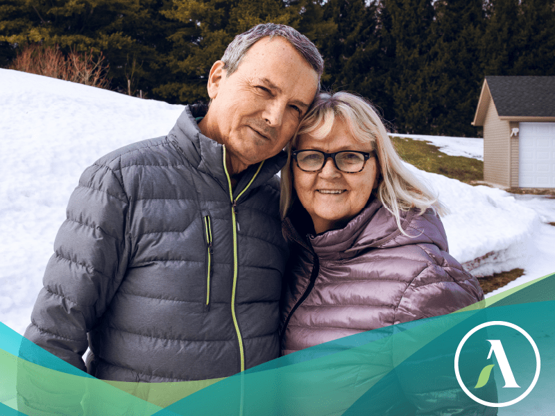 Mature couple smile at camera standing outside in winter.