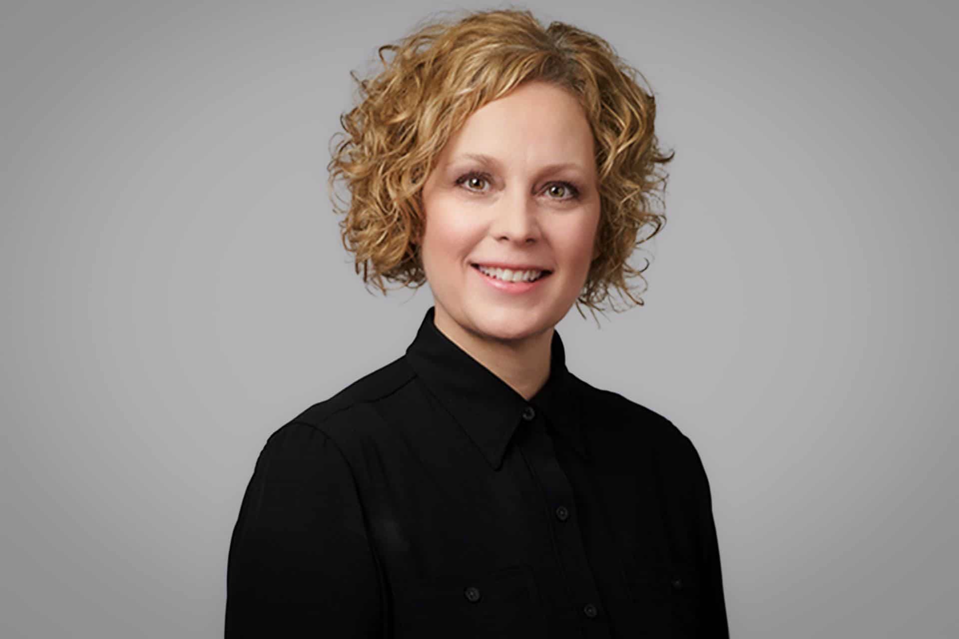 Tammy smiles at the camera, wearing a black dress shirt.