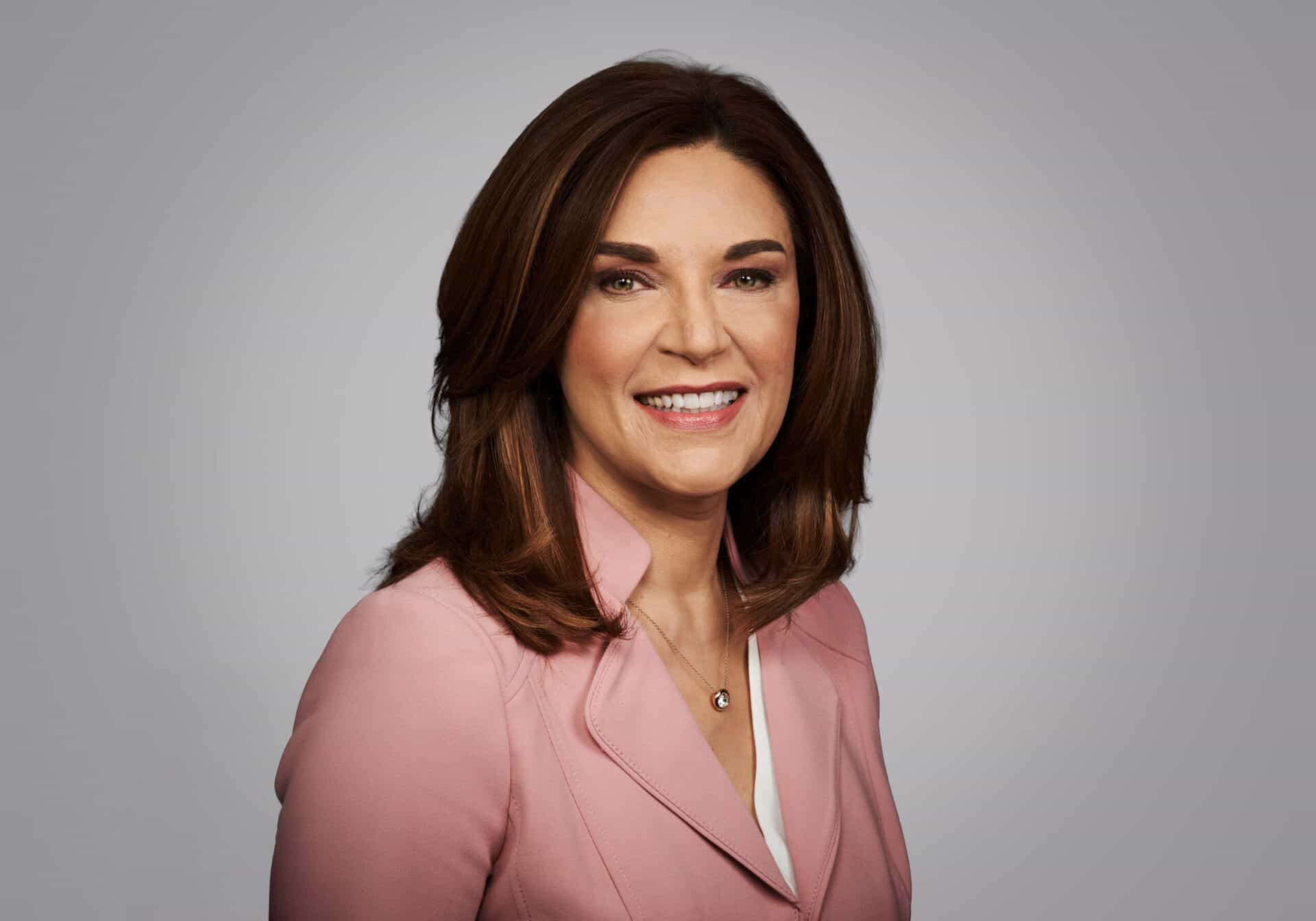 Carolyn smiles at the camera against a grey background.