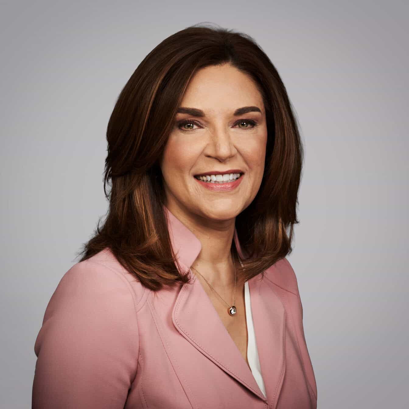 Carolyn smiles at the camera against a grey background.